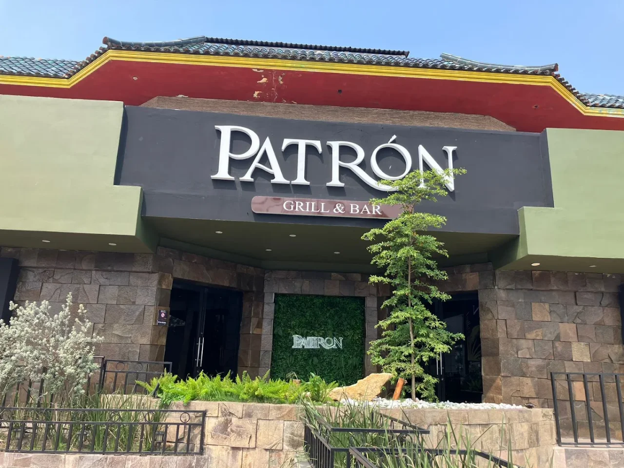 Entrada de Patrón Grill & Bar: fachada de piedra, letrero Patrón y acceso sobre Av. Miguel Hidalgo 3302
